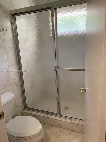 a white toilet sitting next to a shower
