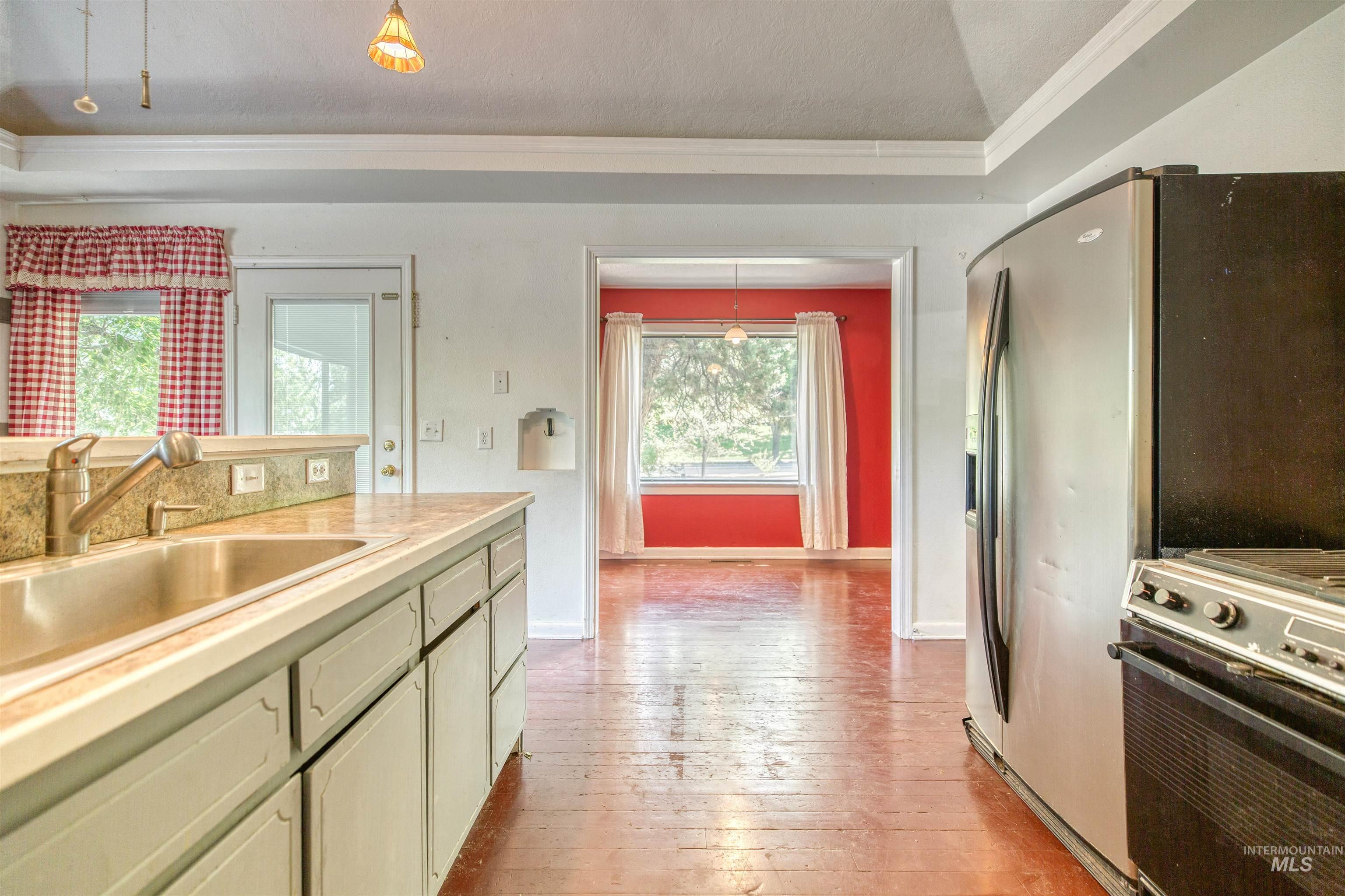 1119 North Eagle Road Eagle, ID 83616 - Photo 14 of 26 Kitchen with crown molding, stainless steel appliances, light countertops, green cabinetry, and light wood-style flooring