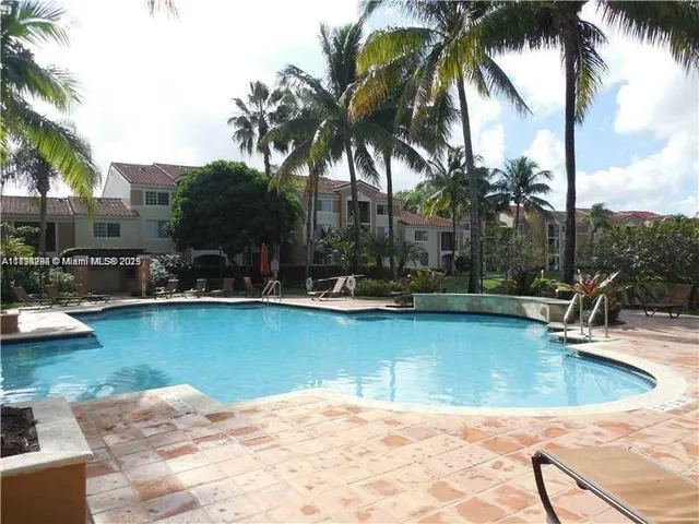 a view of a swimming pool with a lawn chairs under palm trees