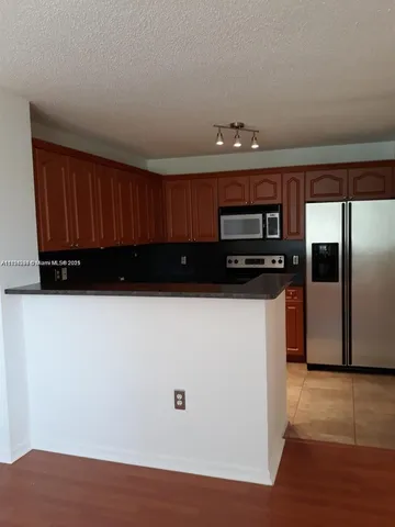 a view of a refrigerator in kitchen and an empty room