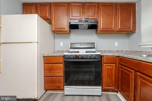 a kitchen with stainless steel appliances granite countertop a refrigerator stove a sink and dishwasher with wooden cabinets