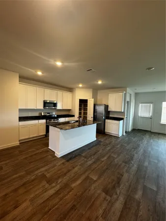 a large kitchen with kitchen island a sink dishwasher a stove and a refrigerator with wooden floor