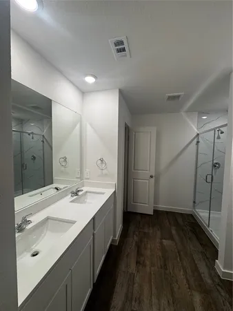 a bathroom with a double vanity sink and mirror with shower