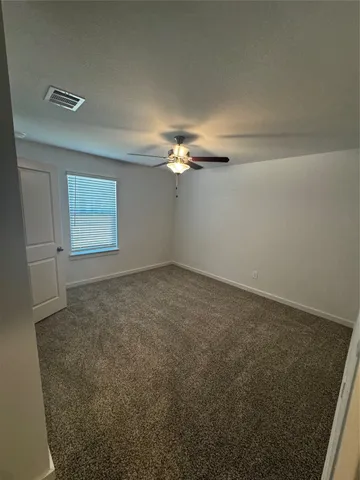 en empty room with windows and chandelier fan
