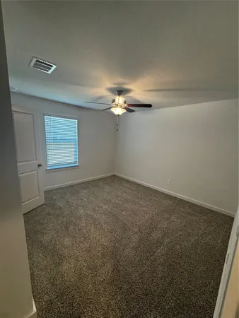 en empty room with windows and chandelier fan