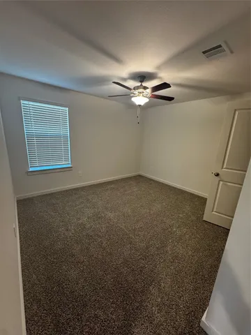 an empty room with a ceiling fan and a window