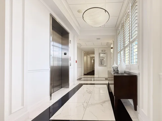 a view of a hallway with wooden floor and a bathroom