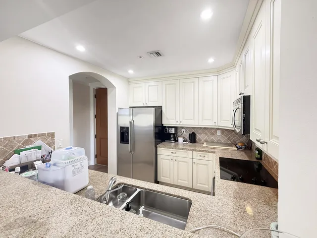 a kitchen with stainless steel appliances granite countertop a sink refrigerator and cabinets