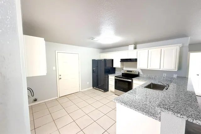 a kitchen with granite countertop a stove sink and refrigerator