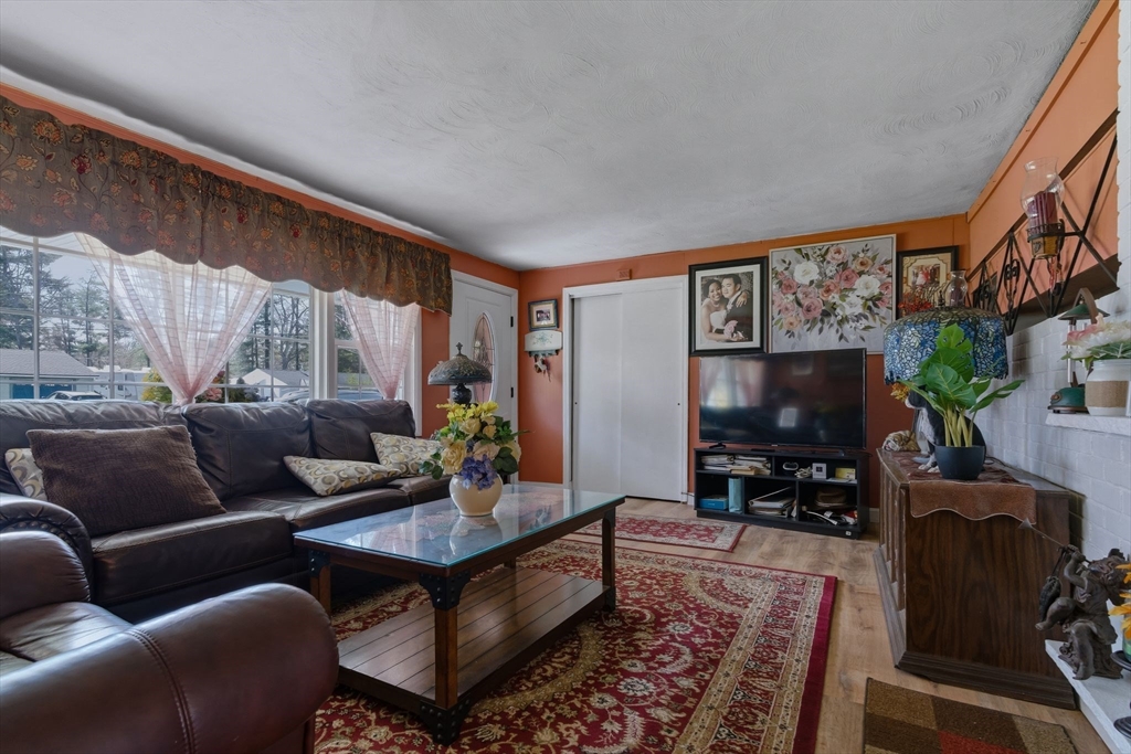 49 Francine Road Raynham, MA 02767 - Photo 10 of 31 a living room with furniture a flat screen tv and a floor to ceiling window