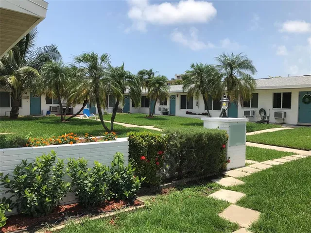 a front view of a house with a yard and potted plants