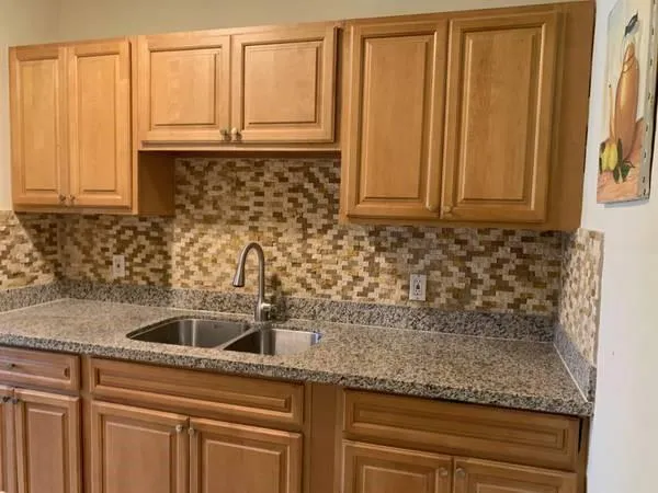 a kitchen with granite countertop a sink a stove and cabinets