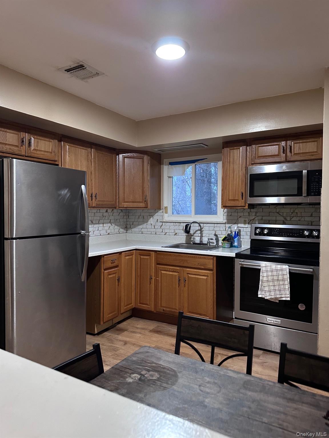 20 Broadway Mastic, NY 11950 - Photo 3 of 11 a kitchen with granite countertop a refrigerator and a stove top oven