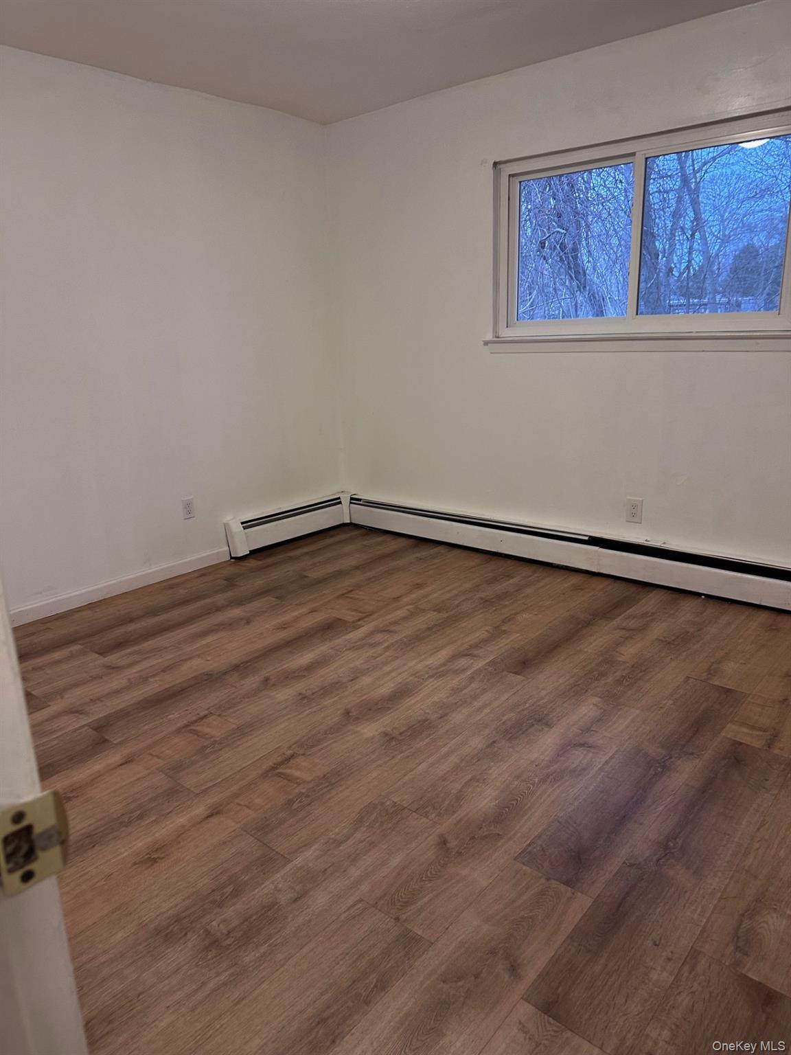 20 Broadway Mastic, NY 11950 - Photo 10 of 11 a view of an empty room with a window and wooden floor