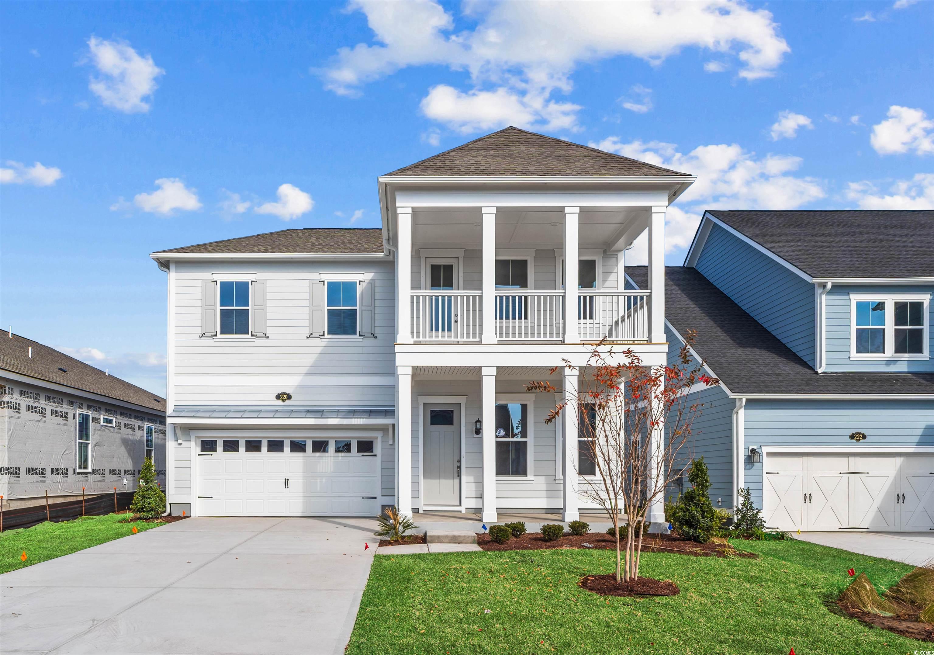 View of front of house featuring a front lawn, driveway, covered porch, a garage, and roof with shingles