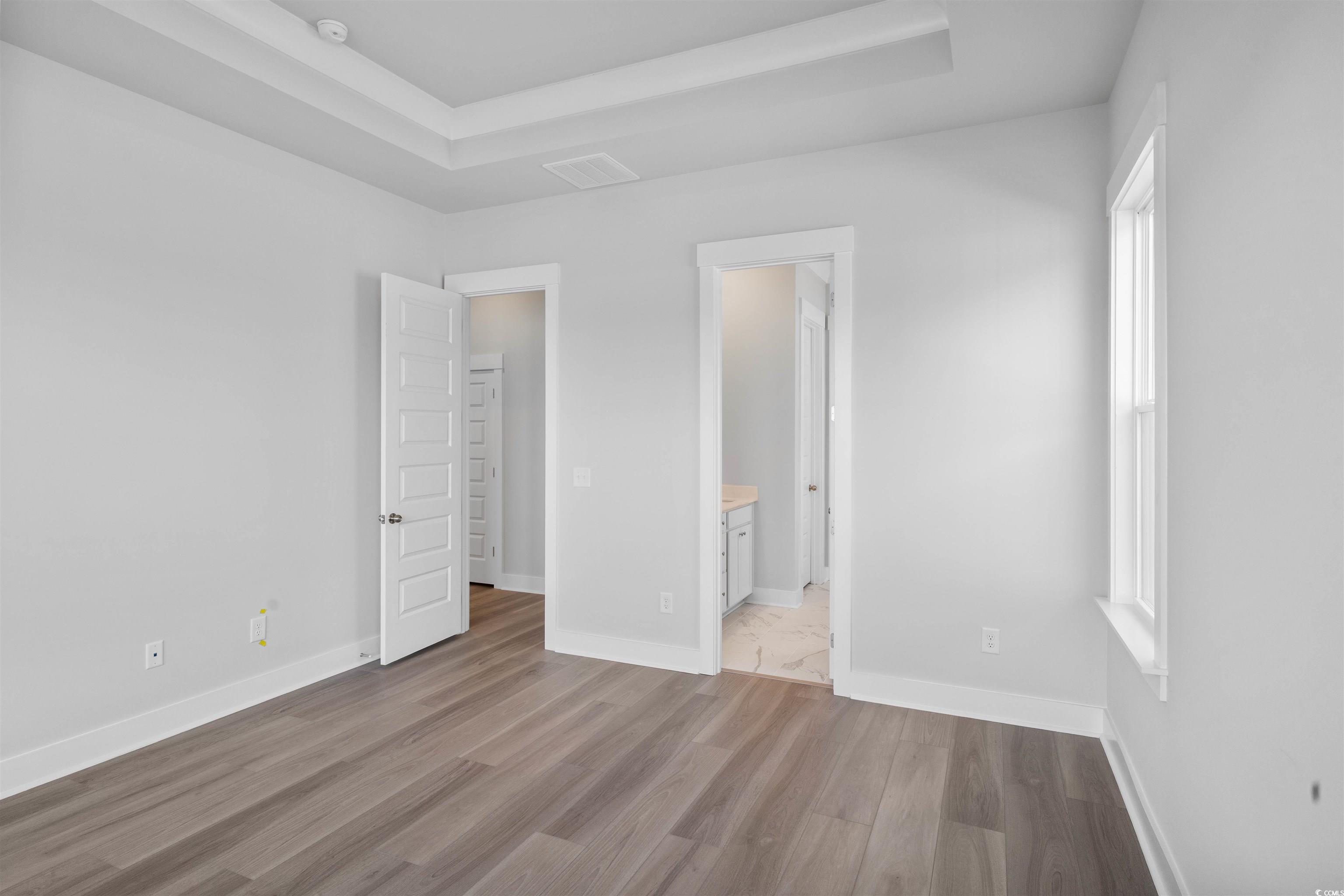220 Atlantic Breeze Street Myrtle Beach, SC 29572 - Photo 24 of 38 Unfurnished bedroom featuring a tray ceiling, light wood-style flooring, and connected bathroom