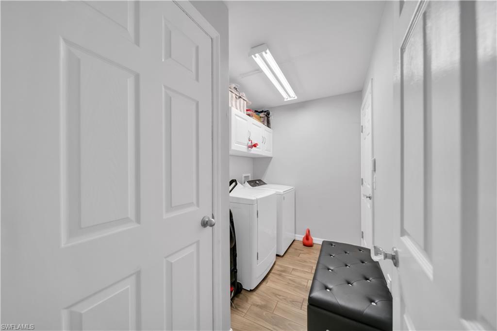 175 Shadowview Court Lehigh Acres, FL 33974 - Photo 15 of 39 Laundry room featuring light wood-type flooring, washing machine and clothes dryer, and cabinet space