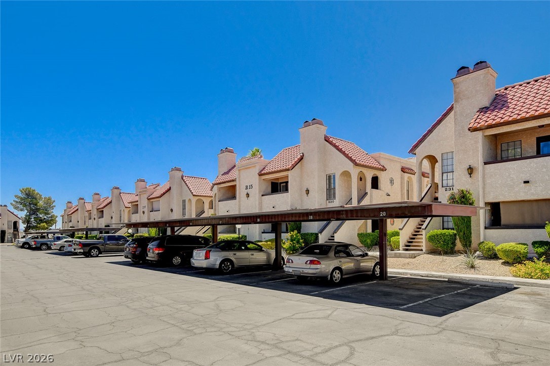 1751 East Reno Avenue, Unit 228 Las Vegas, NV 89119 - Photo 2 of 39 Multi-family residential complex with covered parking, lush landscaping, and tile roofs offers convenient living.