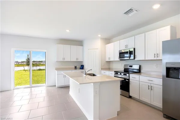 a kitchen with stainless steel appliances granite countertop white cabinets sink and window