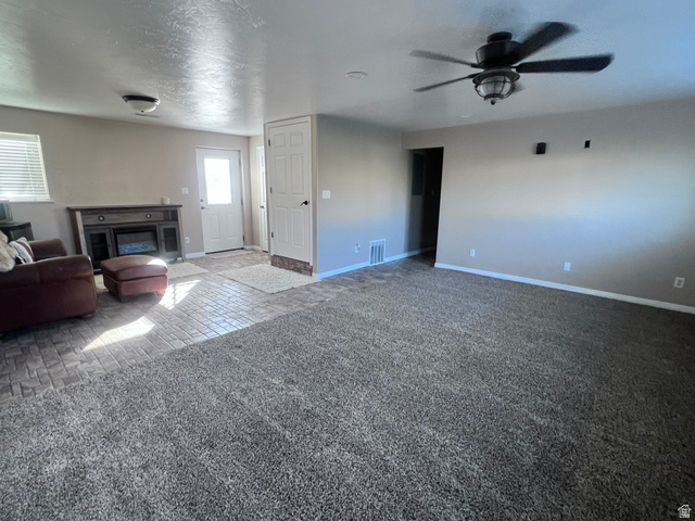 2815 Gordon Creek Road Price, UT 84501 - Photo 3 of 13 Spacious living area featuring neutral carpeting, a built-in electric fireplace console, a ceiling fan, and light-toned walls