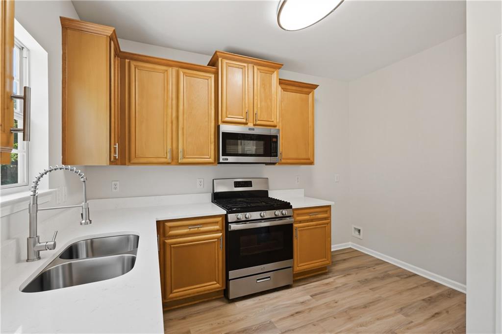6065 Hemperly Road College Park, GA 30349 - Photo 5 of 18 a kitchen with granite countertop a stove a sink and a microwave with wooden floor