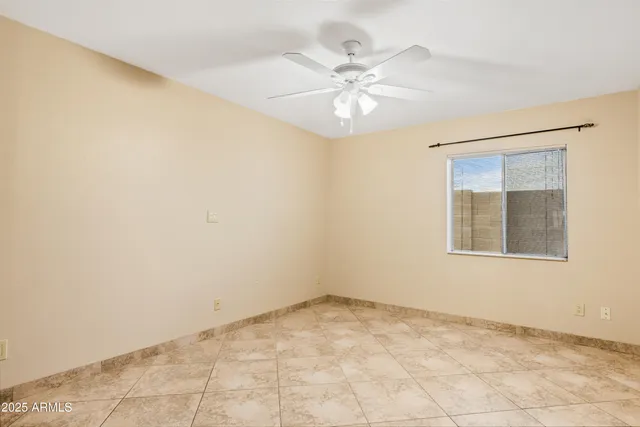 an empty room with a chandelier fan and windows