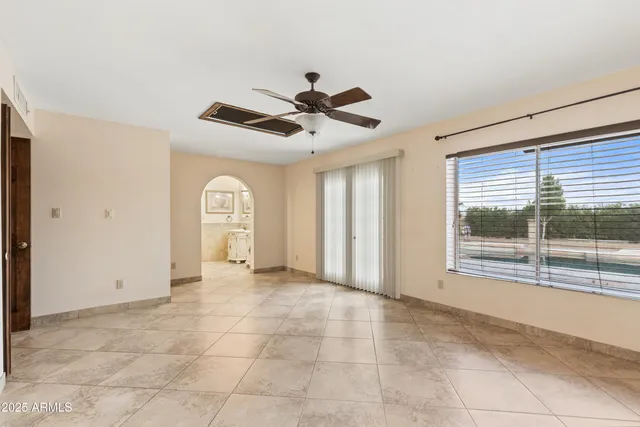 a view of n empty room with window and a kitchen