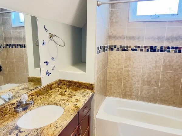 a bathroom with a granite countertop sink and a bathtub