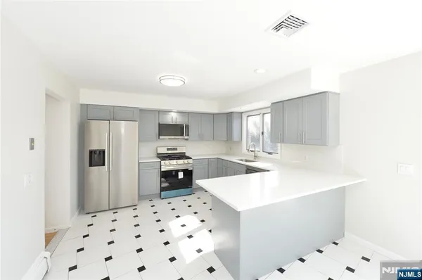 a kitchen with stainless steel appliances a sink a stove a refrigerator and cabinets