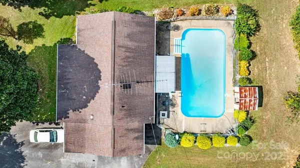 an aerial view of a house with swimming pool and large trees