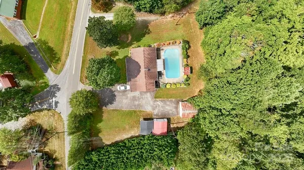 an aerial view of a house with a yard lake and trees all around
