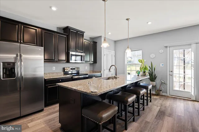 a open kitchen with stainless steel appliances granite countertop a stove a refrigerator a sink a dining table and chairs