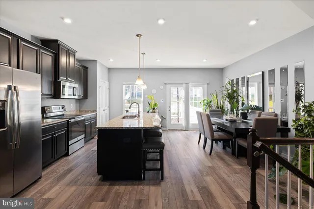 a kitchen with stainless steel appliances a dining table chairs stove refrigerator and cabinets