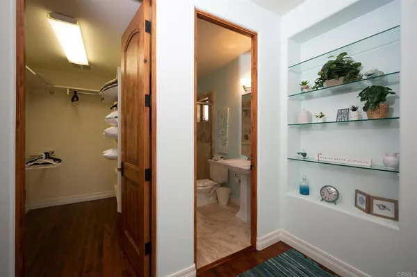 a view of a hallway with wooden floor and a bathroom