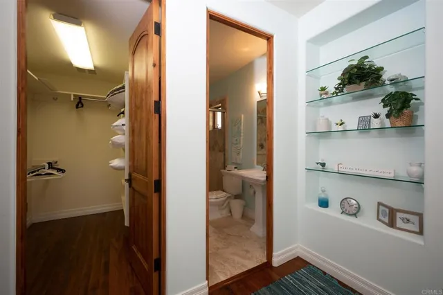 a view of a hallway with wooden floor and a bathroom