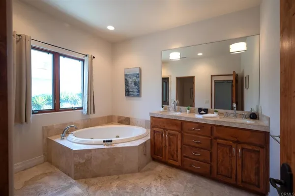 a bathroom with a tub a sink double vanity granite and a large mirror