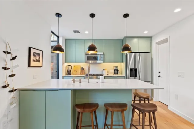a kitchen with stainless steel appliances granite countertop a sink a stove and a wooden floors