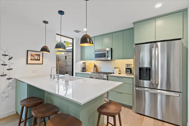 a kitchen with stainless steel appliances a refrigerator a sink a stove and white cabinets