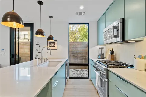 a kitchen with stainless steel appliances granite countertop a sink a stove and a refrigerator