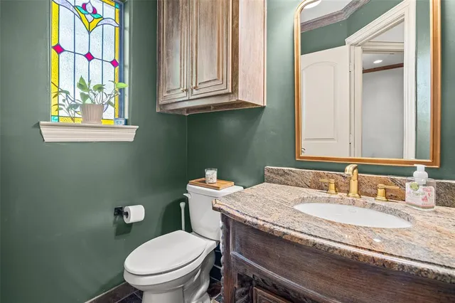 a bathroom with a granite countertop toilet sink and mirror