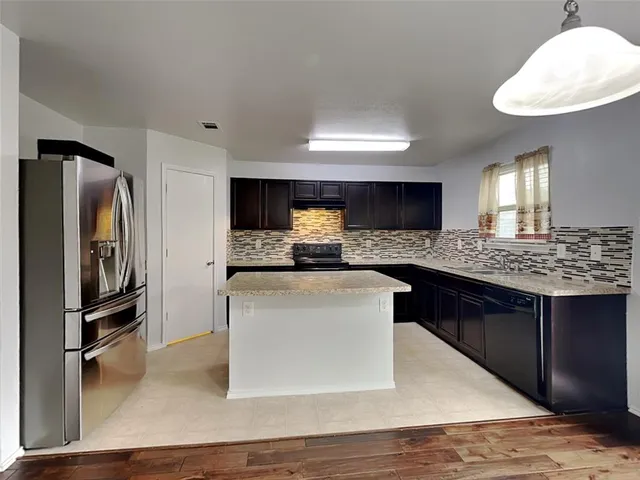 a kitchen with stainless steel appliances granite countertop a refrigerator a stove a sink and a refrigerator