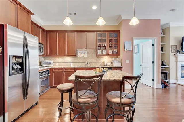 a kitchen with granite countertop kitchen island stainless steel appliances a stove refrigerator sink and cabinets