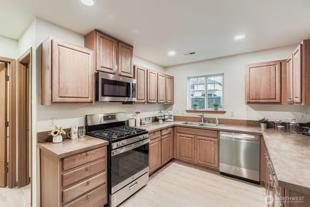 a kitchen with granite countertop a sink stainless steel appliances and cabinets