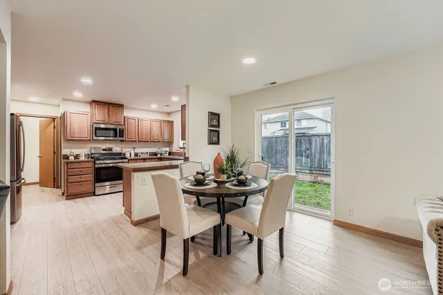 a kitchen with stainless steel appliances a dining table chairs and refrigerator
