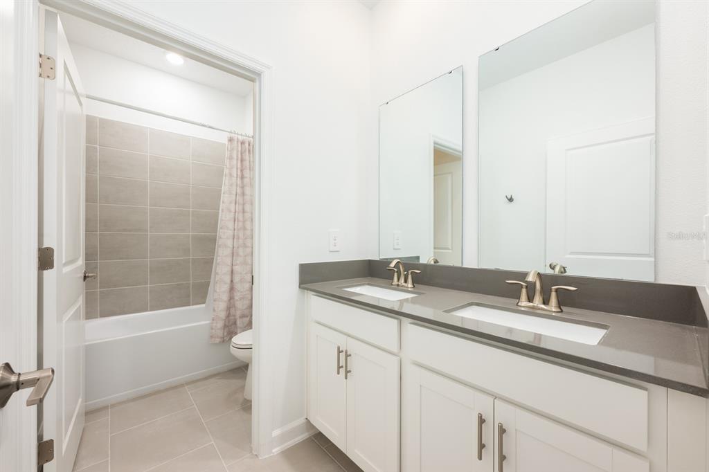 1874 Flourish Avenue Kissimmee, FL 34744 - Photo 15 of 35 a bathroom with a granite countertop sink a mirror a shower and a bathtub