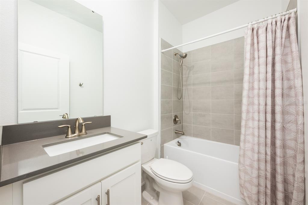 1874 Flourish Avenue Kissimmee, FL 34744 - Photo 18 of 35 a bathroom with a granite countertop sink a toilet and shower
