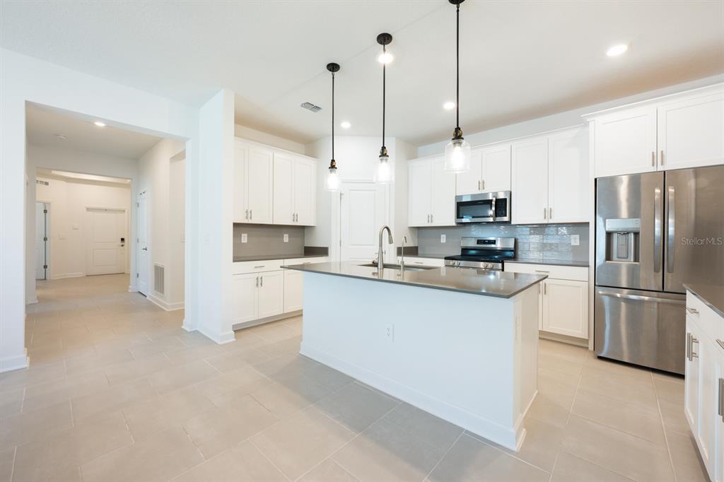1874 Flourish Avenue Kissimmee, FL 34744 - Photo 5 of 35 a kitchen with stainless steel appliances granite countertop a refrigerator a stove a sink and a microwave