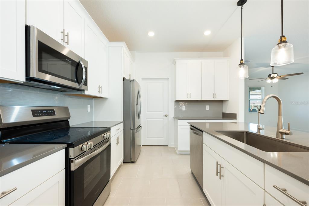 1874 Flourish Avenue Kissimmee, FL 34744 - Photo 6 of 35 a kitchen with stainless steel appliances granite countertop a sink a stove a refrigerator and a microwave