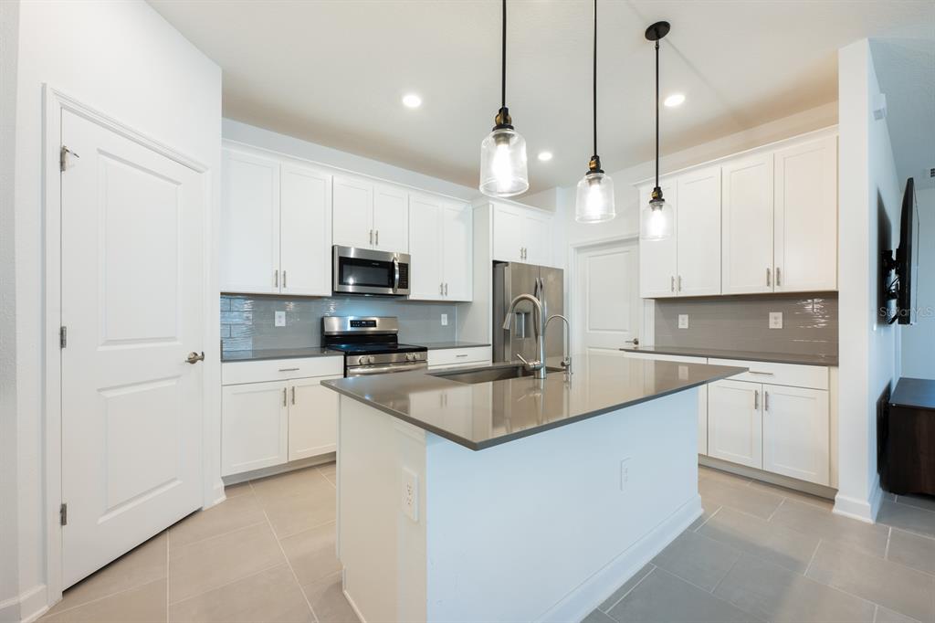 1874 Flourish Avenue Kissimmee, FL 34744 - Photo 7 of 35 a kitchen with kitchen island a white counter top space stainless steel appliances and cabinets
