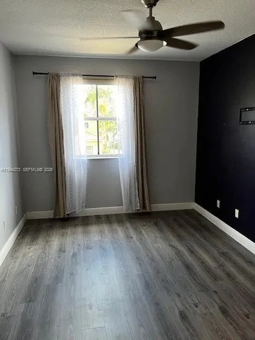 a view of empty room with wooden floor and door